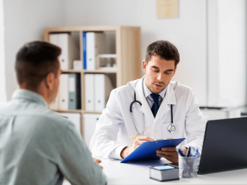 Médico realizando consulta de um homem, analisando seu prontuário